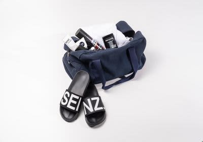 Eine Sporttasche mit Badelatschen von SEINZ. Gefüllt ist die Tasche mit Produkten für die Männerpflege. 